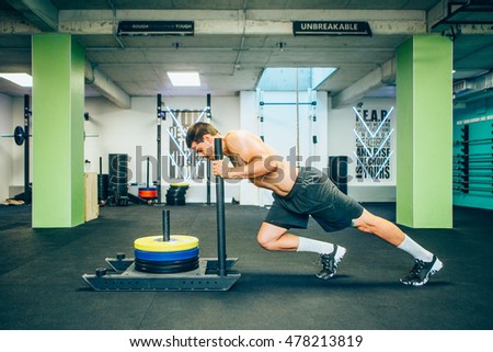 Muscular and strong young man pushing the exercise equipment at the gym
