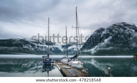 Amazing nature landscape view of lake surrounded by foggy mountains. Sailing vessels or ships. Nature lake. Forest natural. Location: Scandinavian Mountains, Norway. Artistic picture. Beauty world.