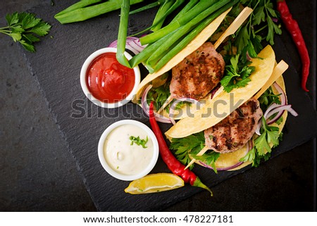 Tortillas tacos with appetizing kebab (meatballs) and sauce on black background. Top view