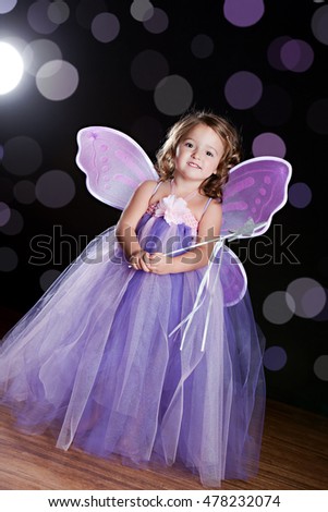 Magical! Adorable toddler wearing a long tutu dress, butterfly wings and holding a magic wand. Background light, lens flare, and "sparkles" for effect.