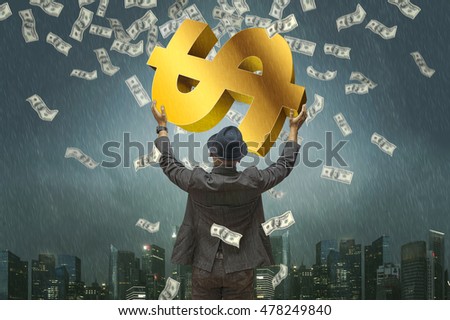 Back view of business man hug money & money symbol with blue dramatic rain & city background. Concept for success business. Motion blur money.