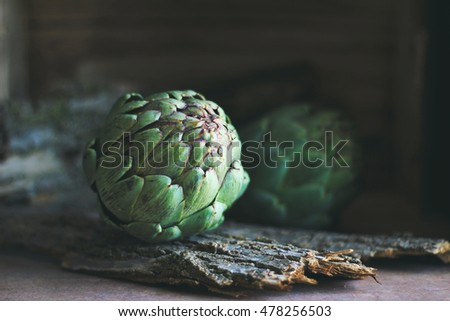 Artichokes with wooden background in dark food photography style