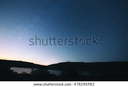 The beautiful night sky with muck of stars and the forest and lake on foreground
