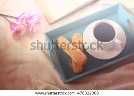 Romantic breakfast in the bed: cookies, hot coffee, flowers and open book. vintage style image , photographed without editing software, using handmade filter
