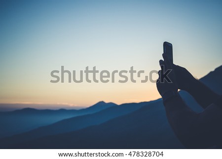 man taking picture with smartphone of sunset light beautiful panorama mountain