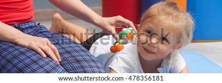Small girl and therapist touching her back with a massage device, panorama