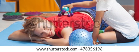 Girl touching her happy therapist with a massage device, panorama