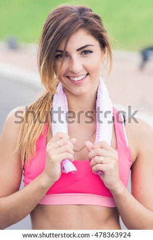 Portrait young attractive smiling fit woman with white towel resting after workout sport exercises outdoors on a background of park trees. Healthy lifestyle well being wellness happiness concept