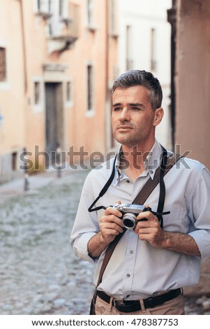 Confident tourist with a digital camera, he is exploring a city and shooting pictures in the street
