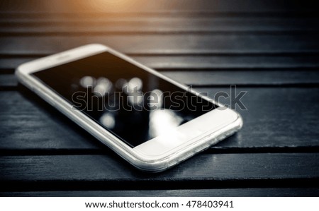 Mockup of Smart phone with blank screen lying on wooden table- sunlight filter effect