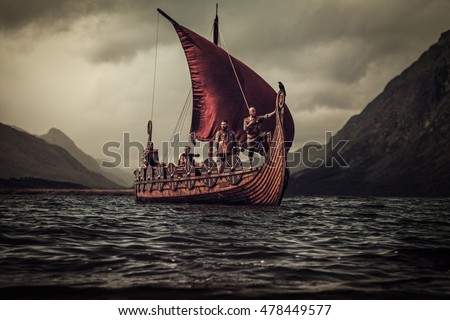Group of vikings are floating on the sea on Drakkar with mountains on the background. Royalty-Free Stock Photo #478449577