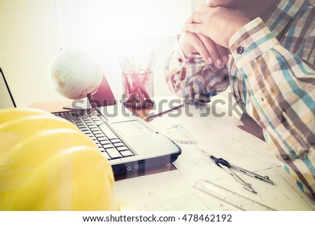 Architect with construction plan on office desk under shinning light. Horizontal, film effect,