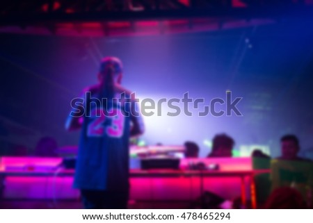 Blurred background : Club, disco DJ playing and mixing music for crowd of happy people. Nightlife, concert lights, flares