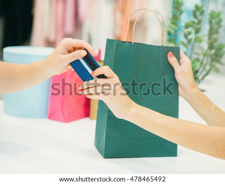 Woman in shop with a credit card in a hand receiving her credit card and shopping bags.Close up.Shopping concept 