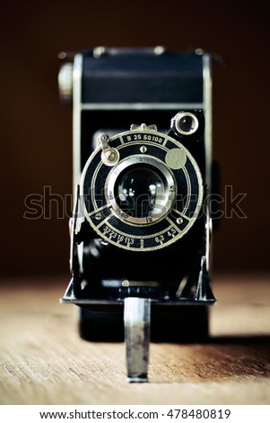 closeup of an old folding camera on a rustic wooden surface