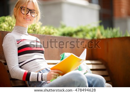 girl with notebooks sitting on bench