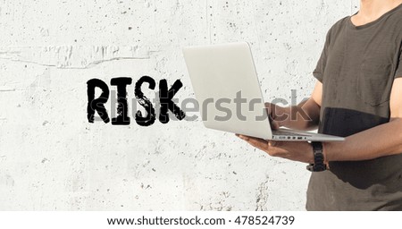 Young man using laptop and RISK concept on wall background