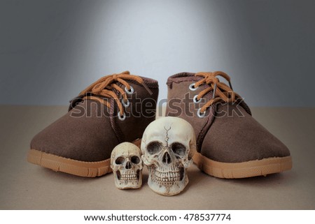 Still Life photography with Human Skull and Baby brown shoes on wooden table