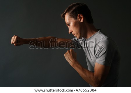 Side view of young handsome man making punches. Low key photography.