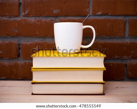 View on the pile of books and cup of tea lying on the wooden table