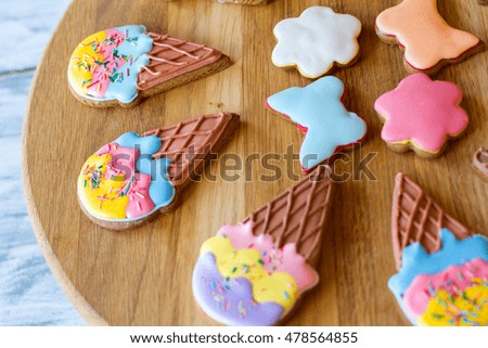Glazed cookies on wooden board. Biscuits shaped as flowers. Desserts for home party. Sugar frosting and crispy dough.