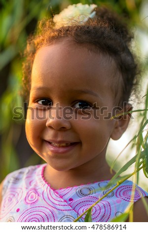 Portrait of a black baby girl close-up. Baby smiles among the leaves