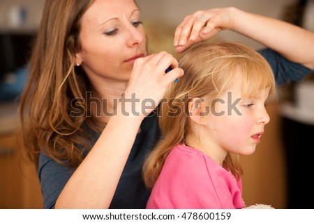 Mother combs hair to a cute little girl