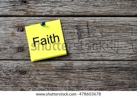 FAITH text written on sticky note on wooden background. Motivational quotes