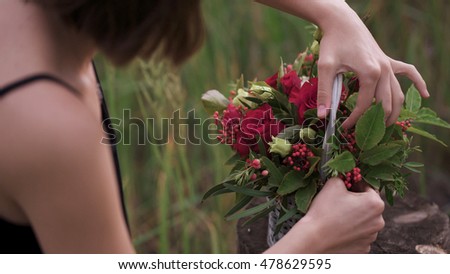 Creation of a flower arrangement of roses. Female hands working with flowers and decorative basket. Professional florist making flower arrangement. Close-up