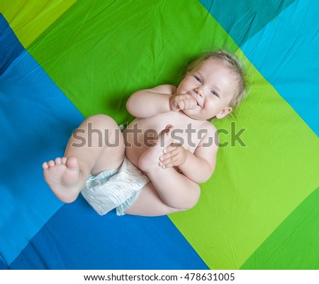 beautiful baby girl laying in white sunny bedroom. Newborn child relaxing on a rug. Nursery for young children. Furniture, textile and bedding for kids.