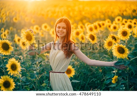 young red-haired woman in a field of sunflowers and sweet smiles. sunset light in the field of sunflowers