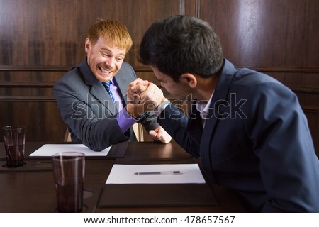 Two Businessmen Arm Wrestling in Modern Office