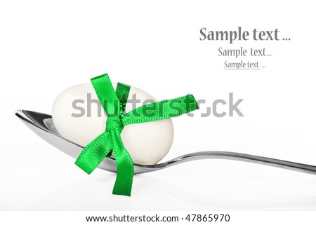 One white egg with a green ribbon on a spoon - on a white background with space for text