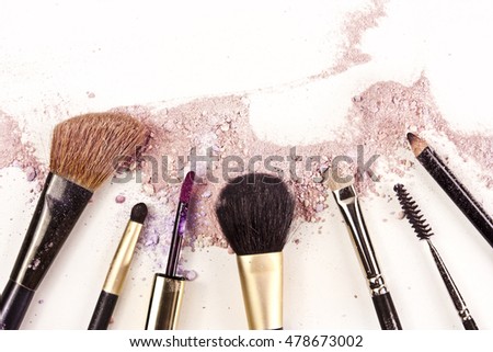 Makeup brushes, lipstick and pencil on a white background, with traces of powder and blush on it; a horizontal template for a makeup artist's business card or flyer design; with copyspace