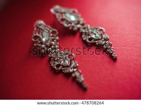 Silver earring swith crystlas lie on the red background