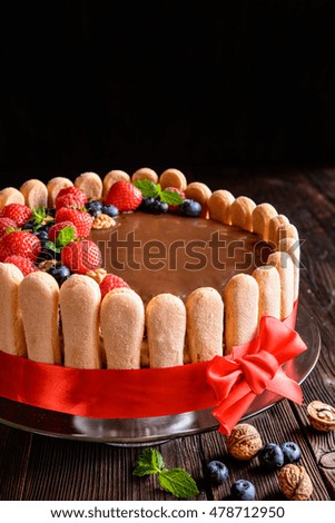 Delicious birthday cake with walnuts filling and strawberries, blueberries and savoiardi biscuit decoration with copy space