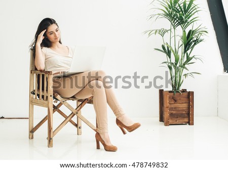 Portrait of an executive professional mature businesswoman sitting on chair in casual and working with laptop near plant. Business ecology concept.