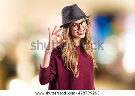 Hipster young girl making OK sign on unfocused background