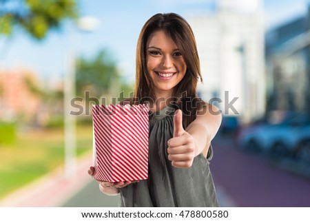 Young brunette girl with popcorns on unfocused background