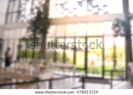 Blurred modern interior office building with glass top table, long transparent windows with green outside