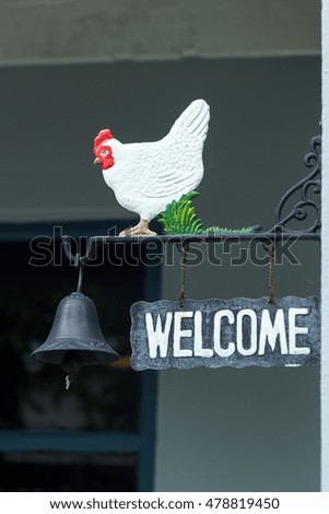 welcome sign with chicken statue and bell