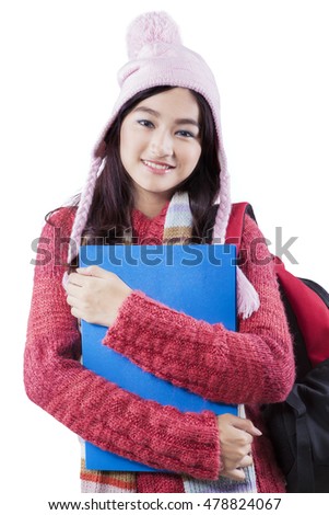 Photo of a pretty high school student carrying bag while wearing winter clothes in the studio, isolated on white background