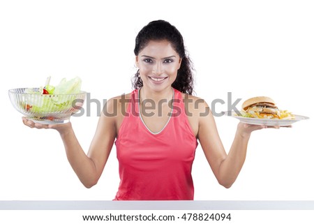 Young woman holding a bowl of fresh salad and hamburger, isolated on white background