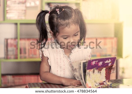Child read, cute little girl reading a book in the library in vintage color tone