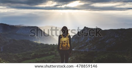 Hipster young girl with backpack enjoying sunset on peak mountain. Tourist traveler on background valley landscape view mockup. Hiker looking sunlight flare in trip in Spain basque country Europa
