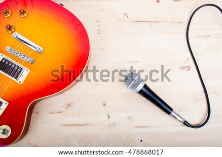 Close up of Electric guitar and microphone on  wood background with space for message  Template music