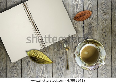A cup of coffee and notebook top on vintage wood table