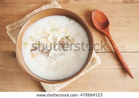 Traditional chinese porridge rice gruel in brown bowl on with wooden spoon on wood table Royalty-Free Stock Photo #478884523