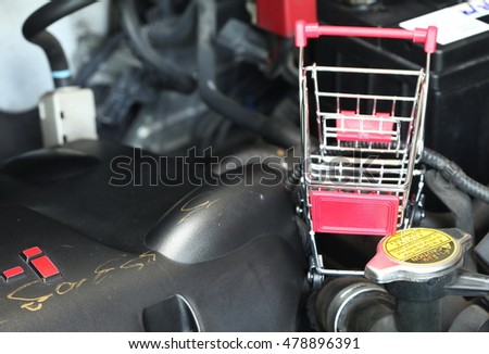 Shopping cart put beside the car radiator cover lid represent the car radiator maintenance and car part background concept related idea.