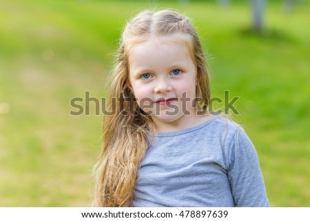 Portrait of a cute girl with long blond hair on nature